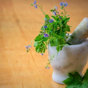 Formations Marble mortar and pestle with fresh herbs and flowers on wooden table enhancing natural health and cooking aesthetics.